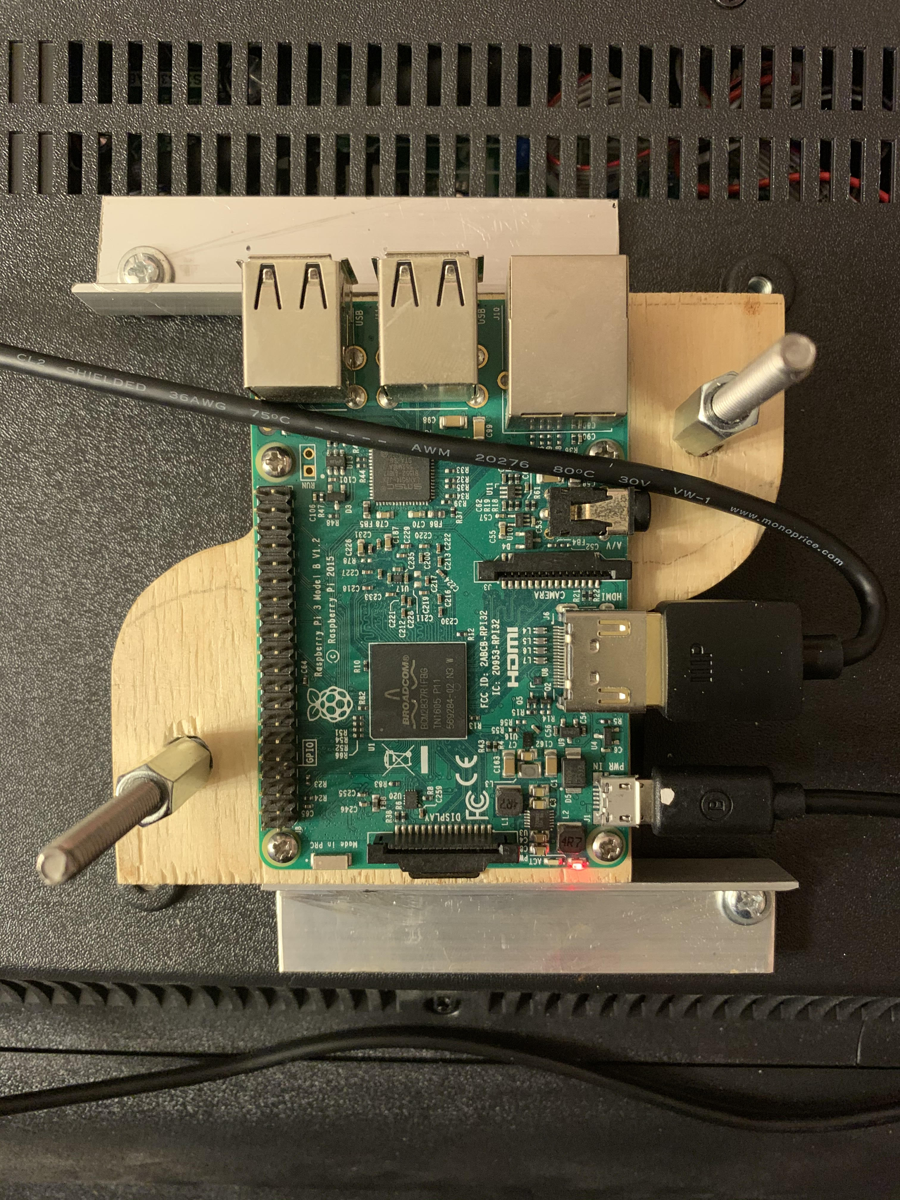 Picture of a raspberry Pi mounted to a wood block, mounted to a Vesa mount